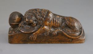 A late 18th century wood carving of a lion recumbent upon military trophies, inscribed '