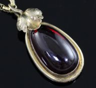 A Victorian gold mounted pear shaped cabochon garnet pendant on oval link chain, with foliate shaped