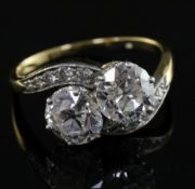 A gold and platinum, two stone diamond crossover ring with diamond set shoulders, the two central