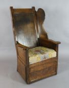 A George III panelled oak wing armchair, with box seat, squab cushion and scroll arms, W.2ft 4in.