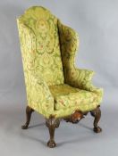An early 18th century style mahogany wing armchair, with ornate scrolled back and sides, on shell