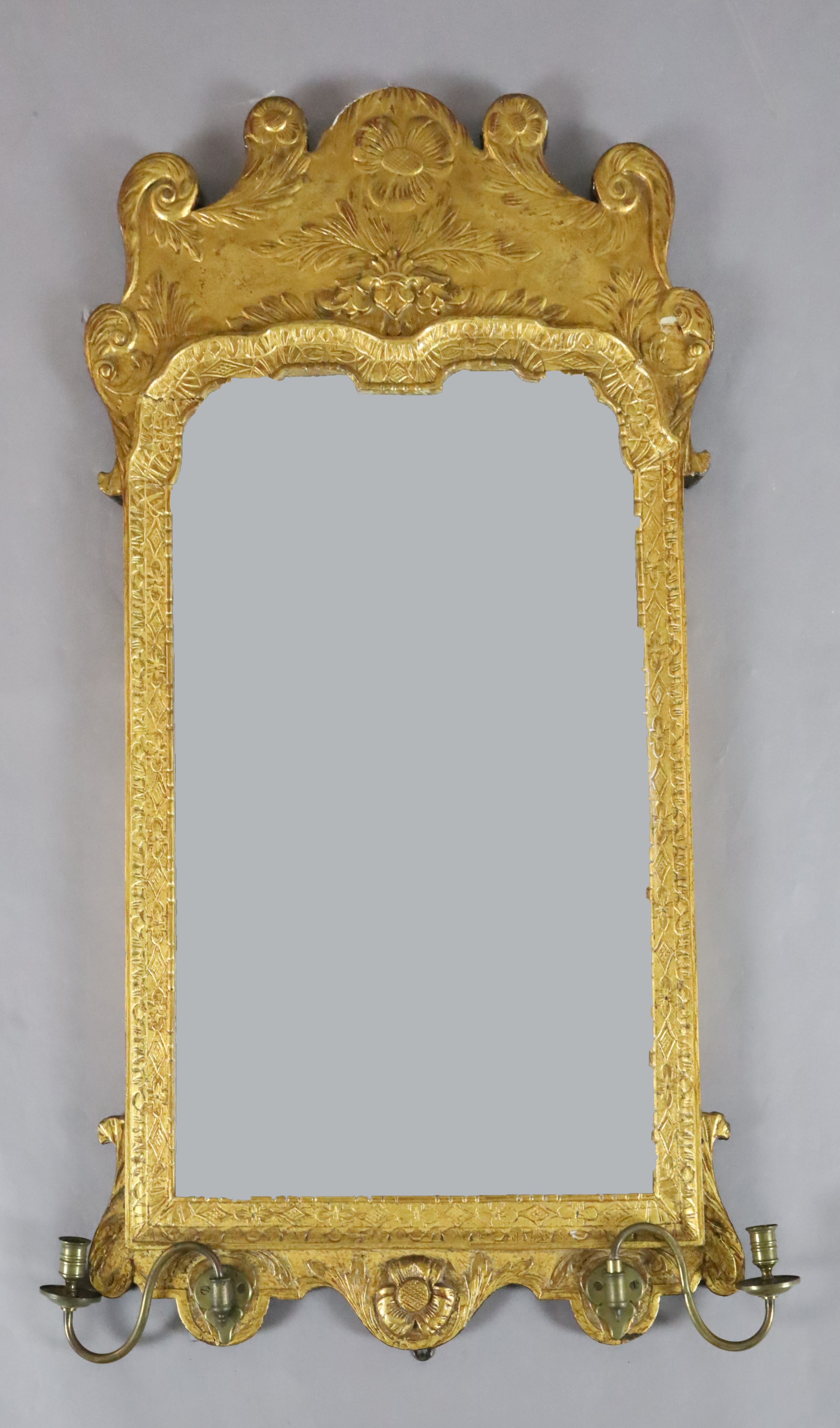 A George II giltwood and gesso wall mirror, with shaped bevelled rectangular plate, flower and