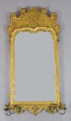 A George II giltwood and gesso wall mirror, with shaped bevelled rectangular plate, flower and