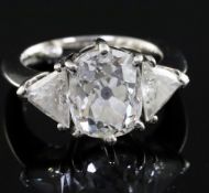 A modern platinum, oval cushion and trillion cut diamond set three stone ring, the central stone