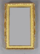 An early 18th century giltwood wall mirror, with rectangular plate and simulated drapery sides, W.