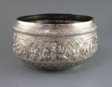 A Burmese silver rice bowl of large proportions with all round embossed scenes of figures,
