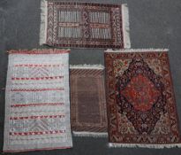 A Caucasian red ground rug, with central blue medallion and three other rugs of varying designs,