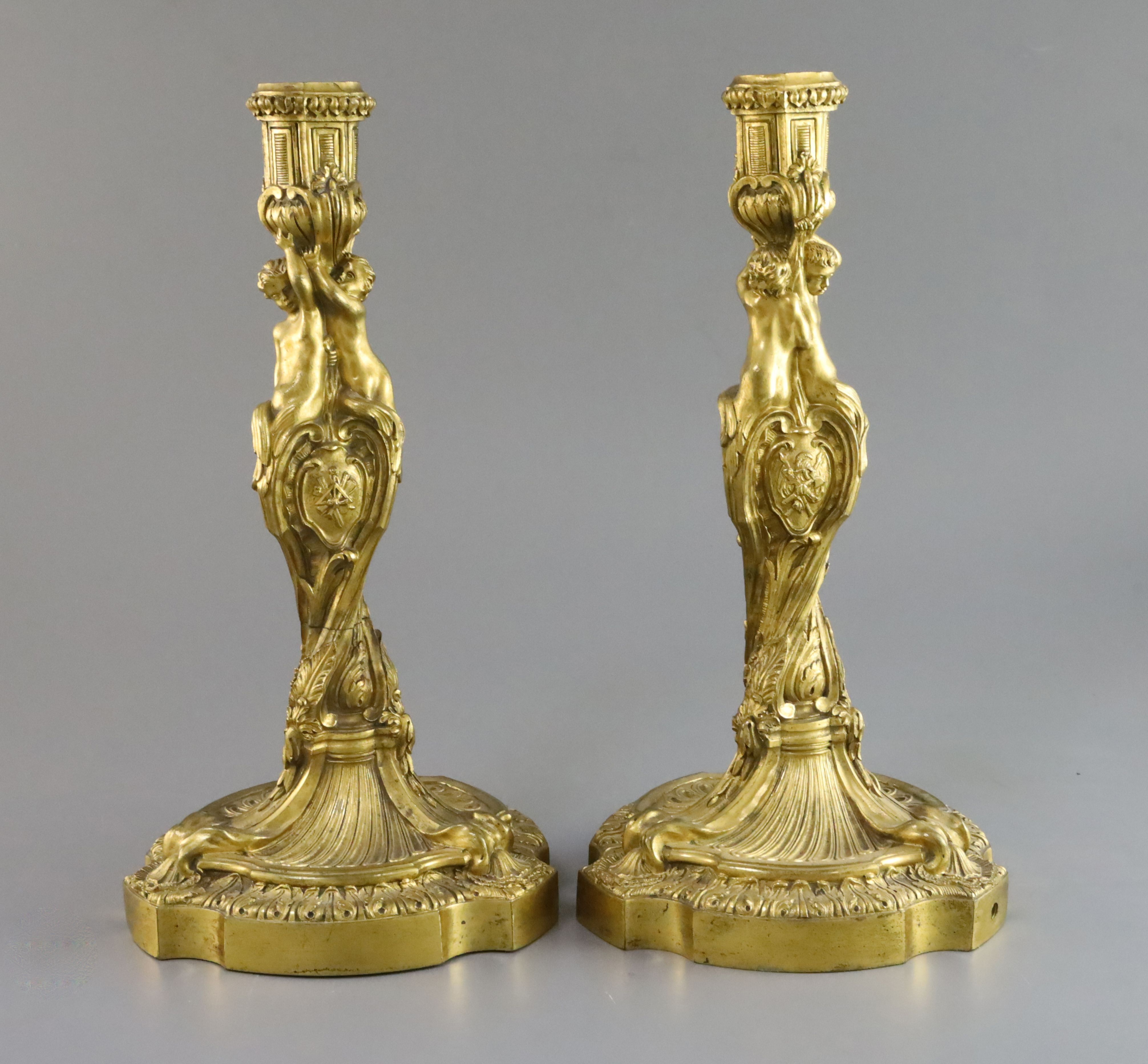 A pair Louis XVI ormolu candlesticks, modelled with putti stems over trophies and swirling foliate