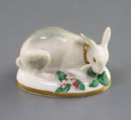 A Rockingham porcelain figure of a recumbent rabbit, c.1830, eating vegetation on the flower