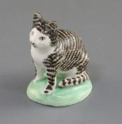 A rare Lowestoft porcelain figure of a seated tabby cat, c.1780, on a green washed mound base,