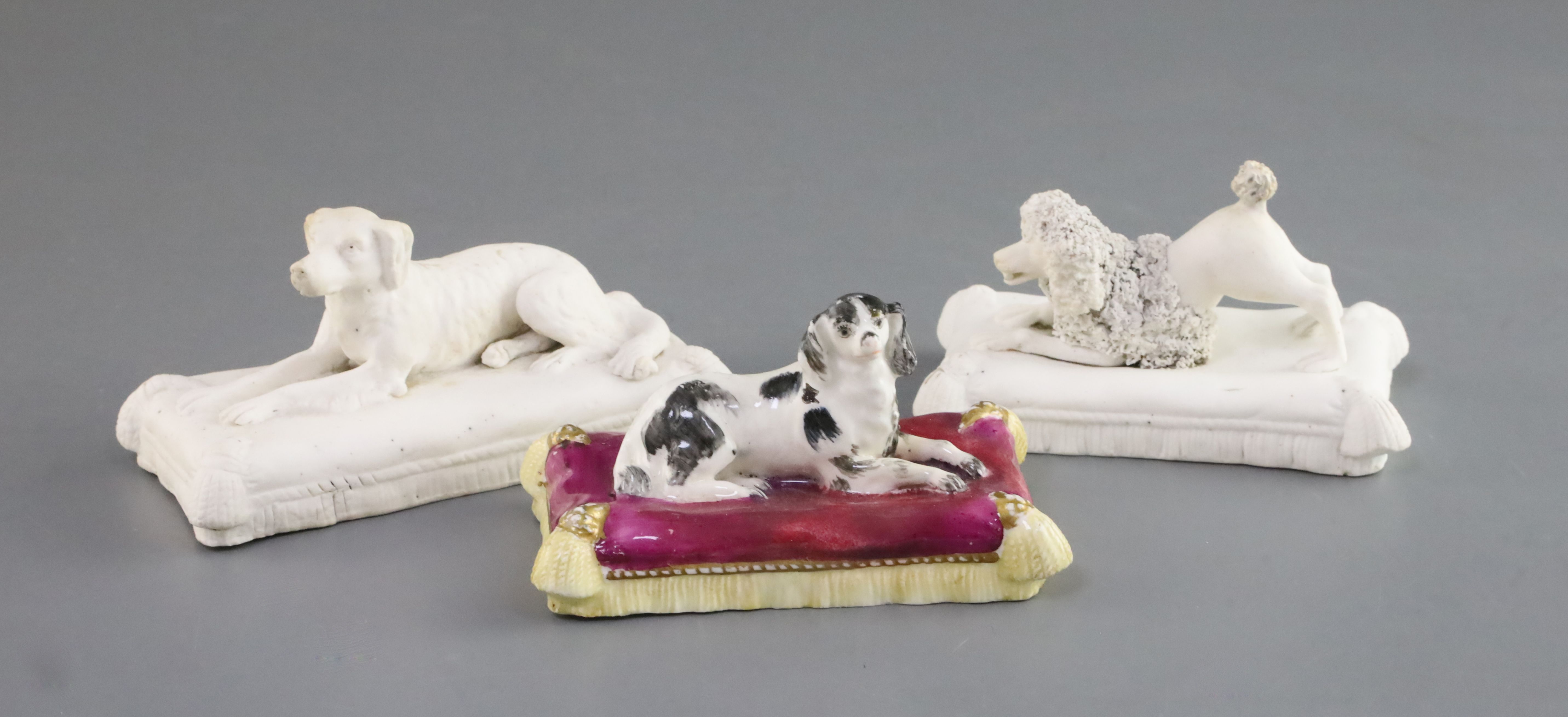 Three Minton porcelain figures of recumbent dogs on tasselled cushions, c.1831-40, the first a