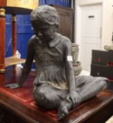 A cast garden statue of a seated girl H.55cm