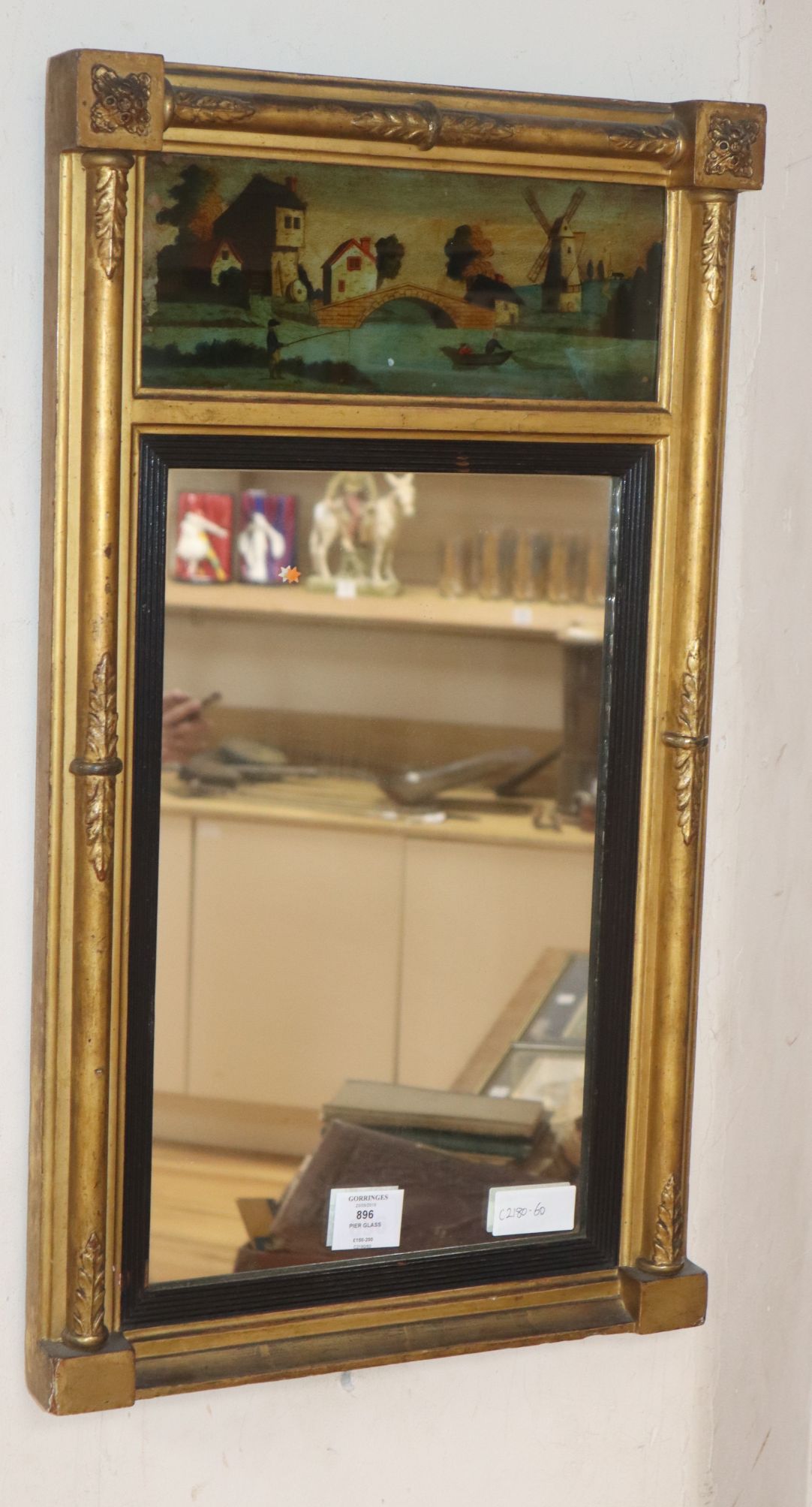 A small Regency gilt frame pier glass, with reverse painted frieze of a windmill in landscape