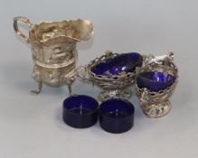 An Edwardian silver cream jug, a pair of salts, four small spoons and four glass liners.