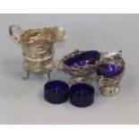 An Edwardian silver cream jug, a pair of salts, four small spoons and four glass liners.