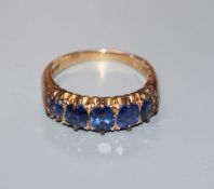 An early 20th century 18ct and graduated five stone sapphire half hoop ring, size N.