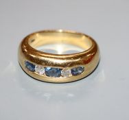 A modern yellow metal and channel set three stone oval cut sapphire and two round cut diamond set