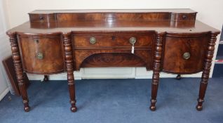 A Regency mahogany sideboard fitted drawers and cupboards on turned reeded legs W.210cm