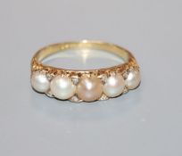 An early 20th century 18ct, graduated split pearl five stone ring, with diamond chip spacers, size