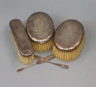 Three silver backed hair brushes and two butter knives, one silver.