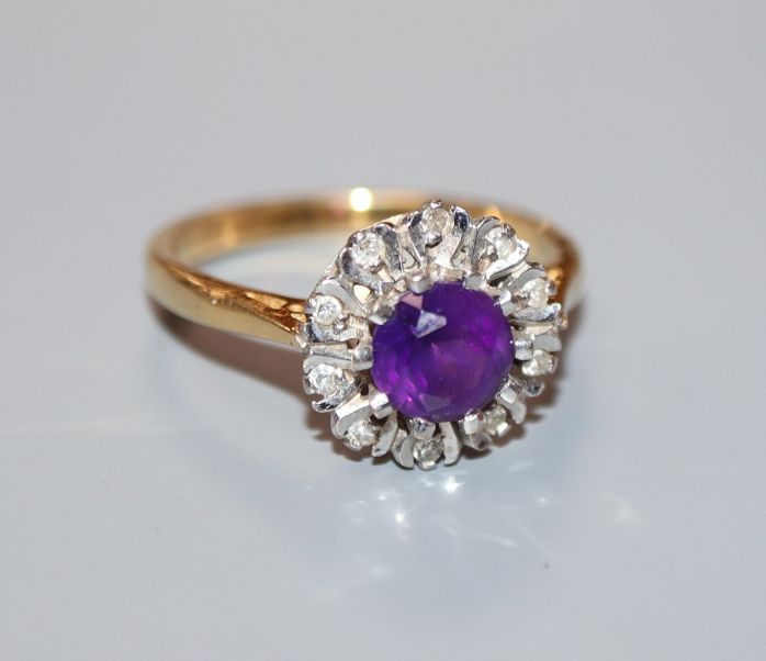 A modern 18ct gold, amethyst and illusion set diamond circular cluster ring, size O.