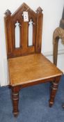 A pair of Victorian Gothic Revival carved oak hall chairs