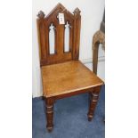 A pair of Victorian Gothic Revival carved oak hall chairs