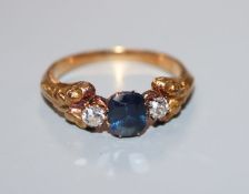 A yellow metal, sapphire and diamond set three stone ring, size L/M.