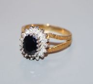 A modern 18ct gold, sapphire and diamond oval cluster ring, with pierced textured shoulders, size S