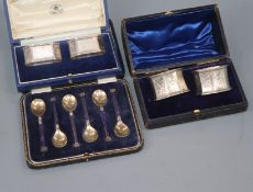 A cased set of six George V silver and enamel coffee spoons and two cased pairs of silver napkin