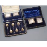 A cased set of six George V silver and enamel coffee spoons and two cased pairs of silver napkin