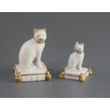 Two Rockingham porcelain figures of cats, c.1830, each seated on a tasselled cushion, the largest