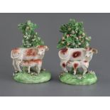 Two similar Derby groups of a cow and calf, c.1820-40, each standing before bocage, on flower