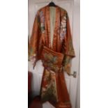 An early 20th century peach silk Japanese kimono, embroidered with polychrome silks of trailing