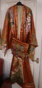 An early 20th century peach silk Japanese kimono, embroidered with polychrome silks of trailing