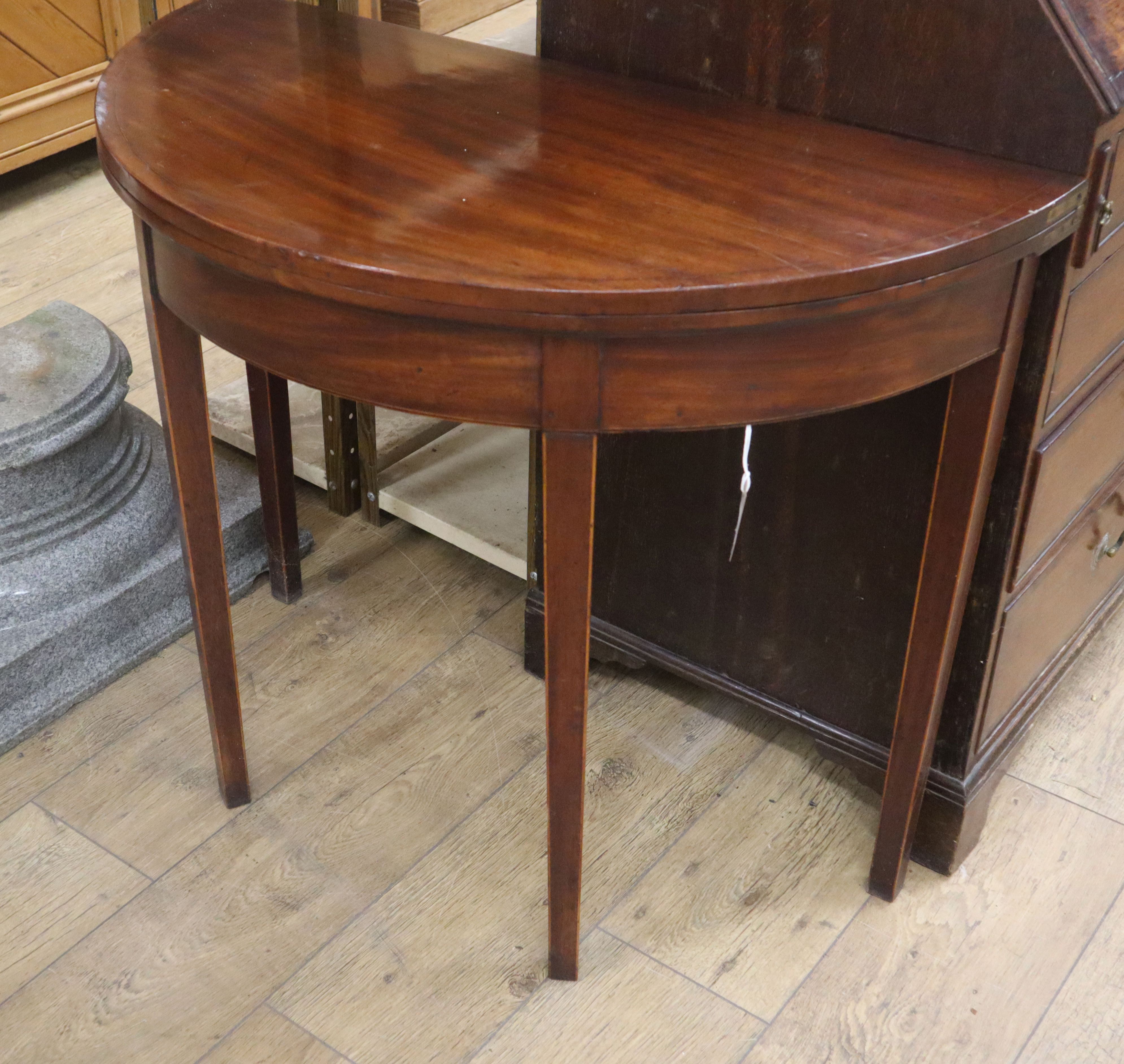 A George III line inlaid mahogany 'D' shaped folding tea table, on square tapered legs W.89cm
