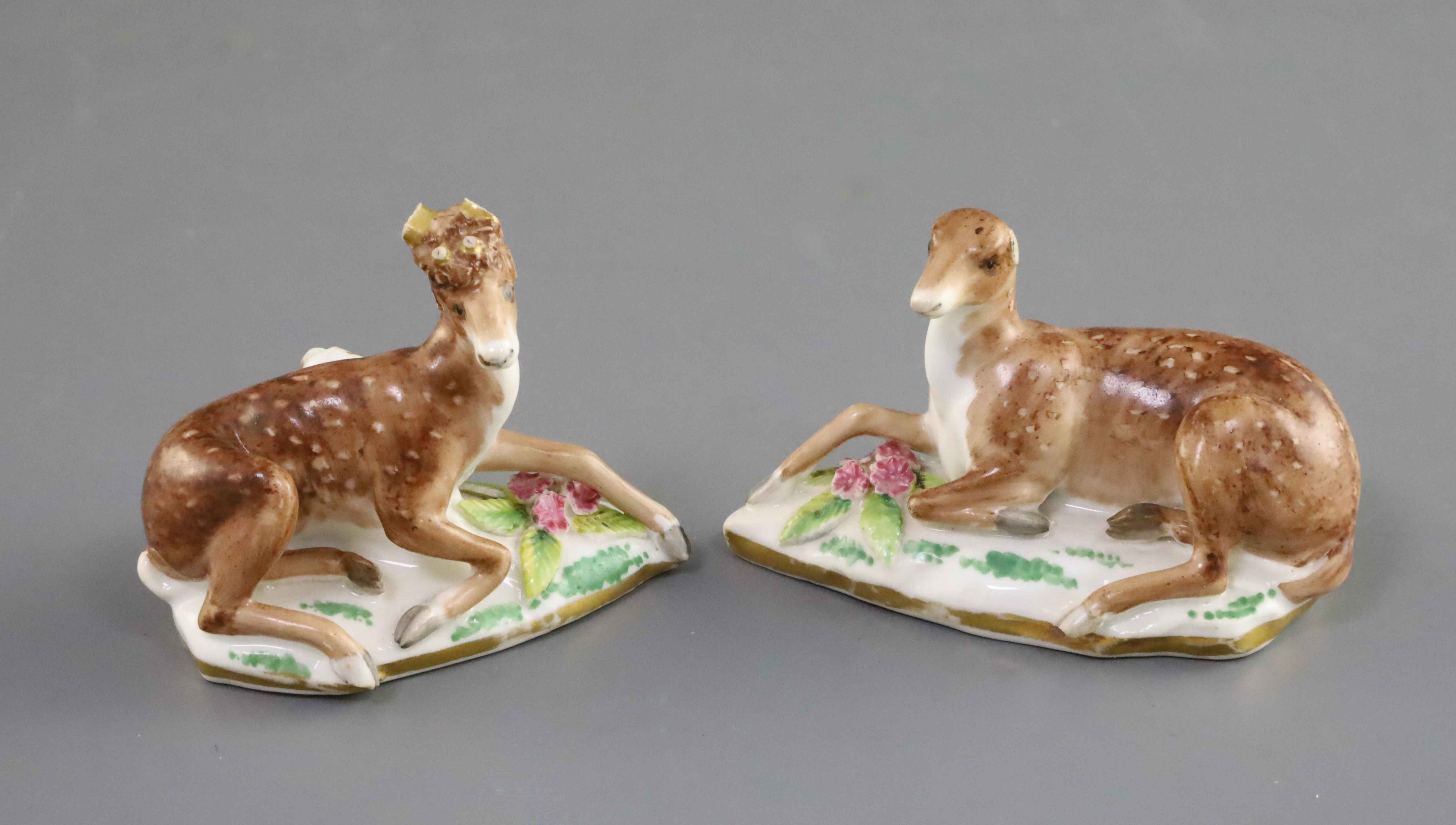 A pair of Rockingham porcelain figures of recumbent deer, c.1830, on shaped flower encrusted