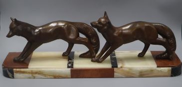 A French Art Deco bronzed metal group of two foxes, on hardstone base length 60cm