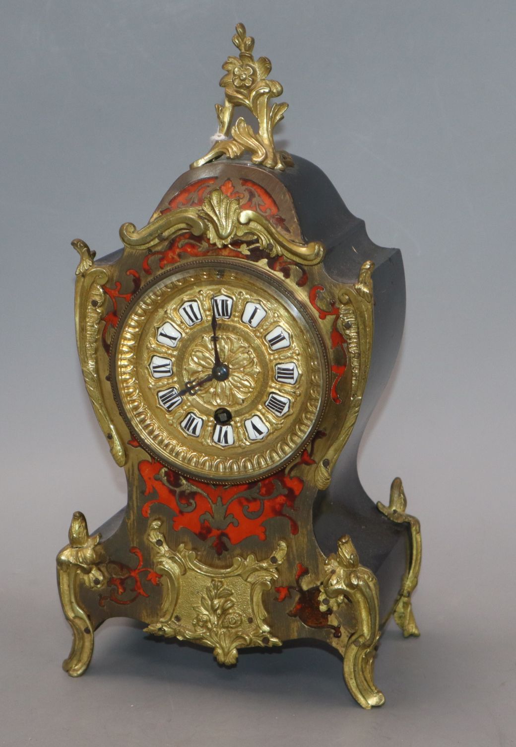 A French red boulle work mantel timepiece, with enamelled Roman numerals