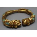 A Tibetan gilt metal and turquoise set open bangle.