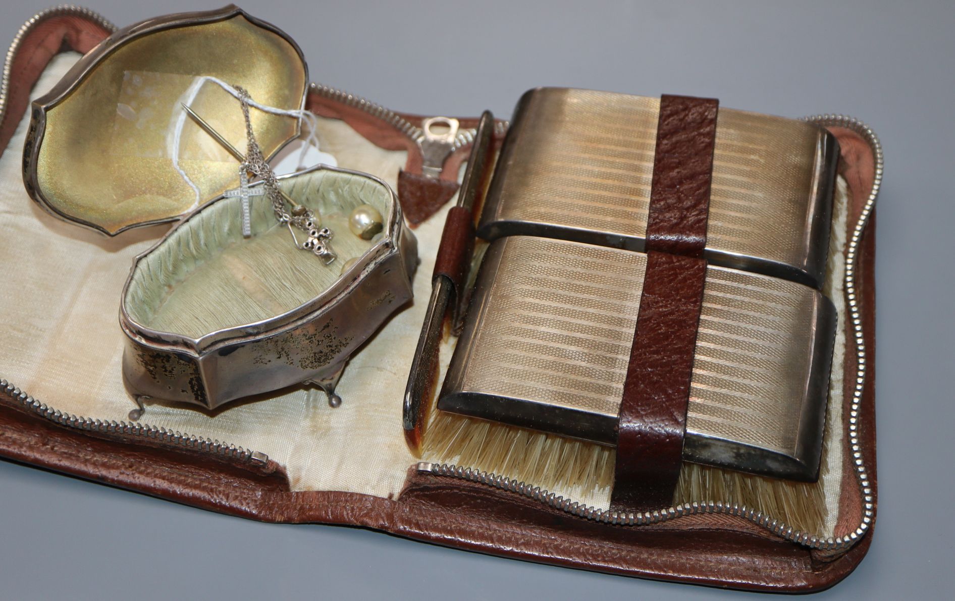 A gentlemen's silver-mounted grooming set in leather case and a silver engine-turned shaped oval