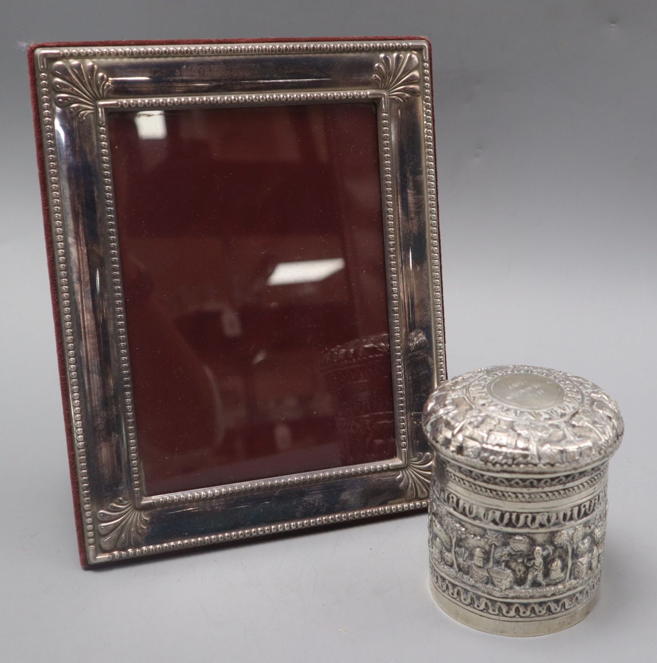 An Indian repousse white metal jar and cover and a silver plated photograph frame.