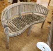 A weathered teak garden 'banana' bench W.150cm