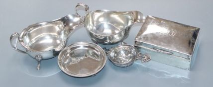 Two silver sauceboats, a silver cigarette box, a silver dish and a silver tea strainer.