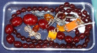 A simulated cherry amber necklace, two amber set brooches, a pair of earrings and a bracelet