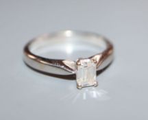 A modern 750 white metal and solitaire emerald cut diamond ring, size J/K