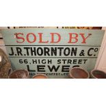 A painted wood sign, c.1960, "Sold by J. R. Thornton 66 High Street Lewes" W.183cm