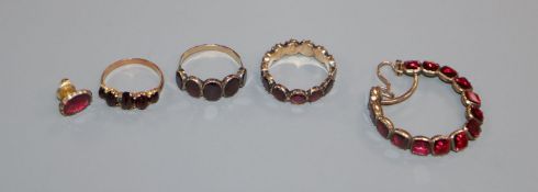 Three assorted Victorian and later yellow metal and garnet set rings and a one odd earring.