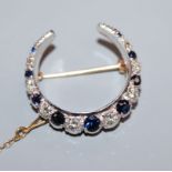 A 9ct yellow and white gold crescent brooch set with sapphires and diamonds, makers FRS Ltd, 27mm.