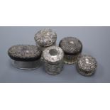 Five assorted early 20th century repousse silver mounted toilet jars, largest 8cm.